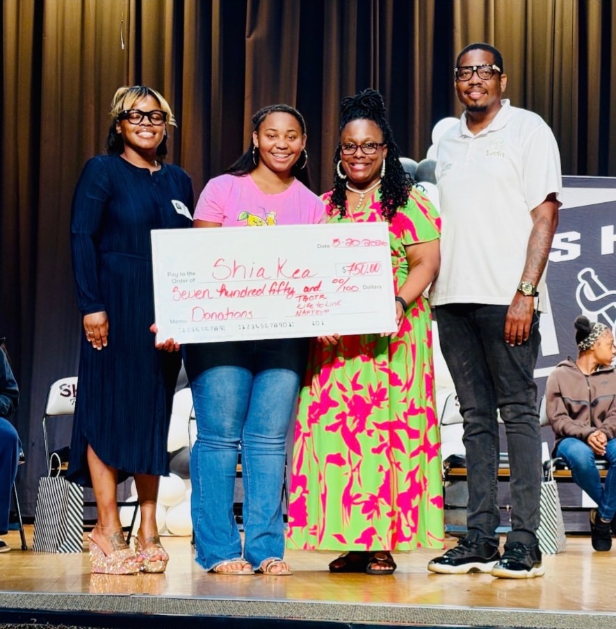Shia Kea and community supporters holding a $750 donation check